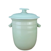 Light green ceramic pot with lid on a white background