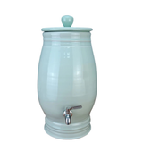 Light green ceramic water dispenser with a silver faucet on a white background